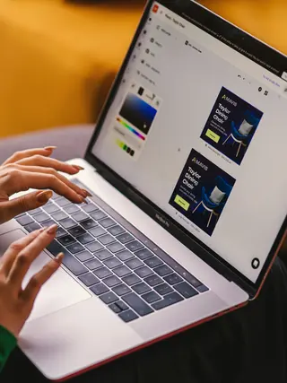 Eine Person erstellt und modifiziert an einem Computer mithilfe eines Marketingtools Display Anzeigen.